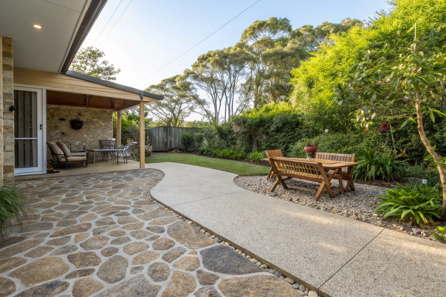 Exposed aggregate concrete patio slab in Coffs Harbour backyard with outdoor furniture and garden surrounds
